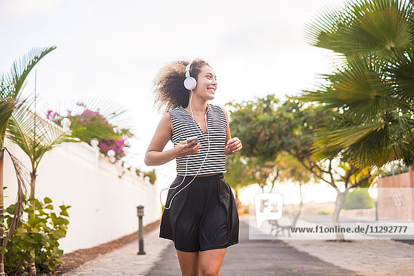 Spanien  junge Frau beim Joggen mit Smartphone und Kopfhörer