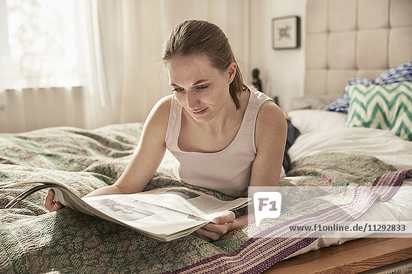 Woman reading newspaper in bedroom
