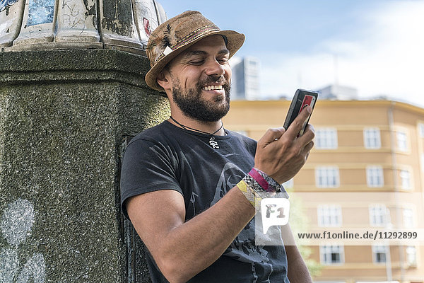 Porträt eines lächelnden Mannes auf seinem Smartphone