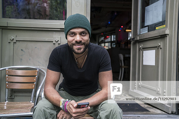 Deutschland  Berlin  Porträt eines lächelnden Mannes vor dem Coffee-Shop