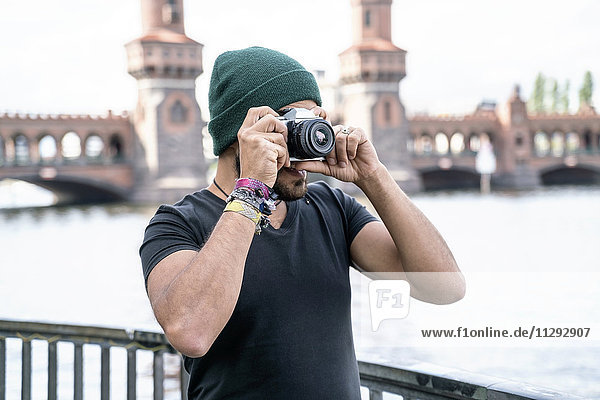 Deutschland  Berlin  Mann fotografiert mit Kamera vor der Oberbaumbrücke