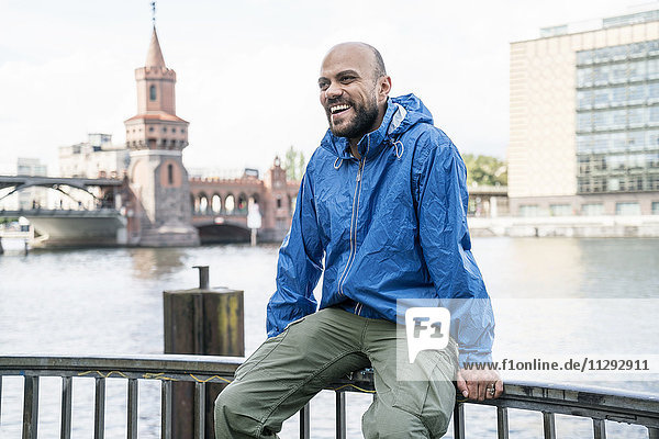 Deutschland  Berlin  lachender Mann in blauer Regenjacke am Geländer vor der Oberbaumbrücke
