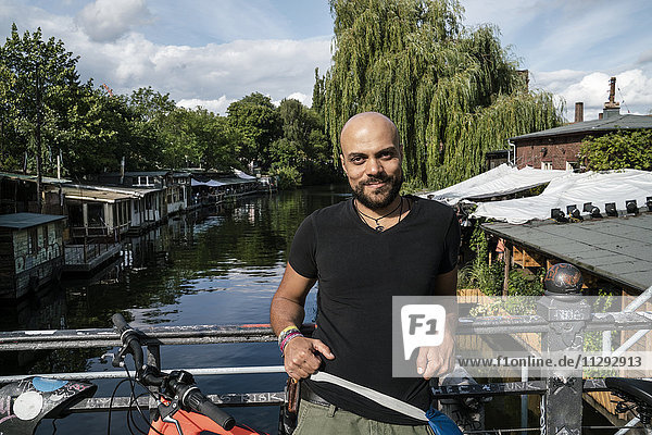 Deutschland  Berlin  Portrait eines Mannes mit Fahrrad auf der Brücke stehend