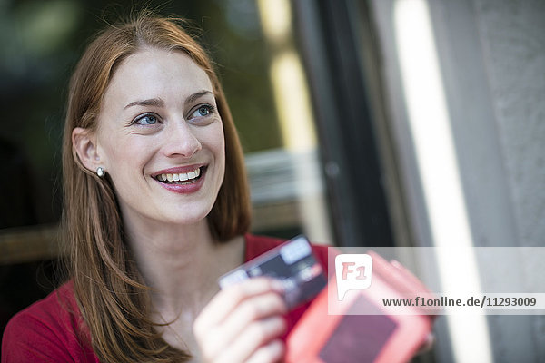 Porträt einer lächelnden Frau mit Geldbörse und Kreditkarte