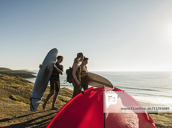 Drei Freunde mit Surfbrettern beim Camping am Meer