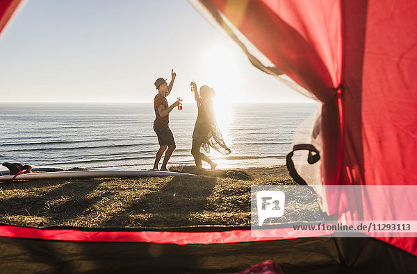 Tanzende junge Paare beim Camping am Meer
