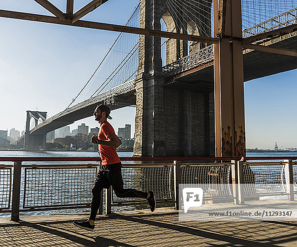 USA  New York City  man running at East River under Brooklyn Brige