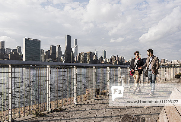 USA  New York City  two businessmen walking along East River