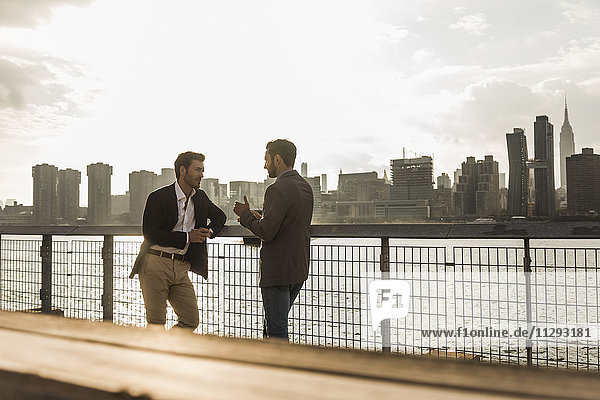 USA  New York City  two businessmen talking at East River