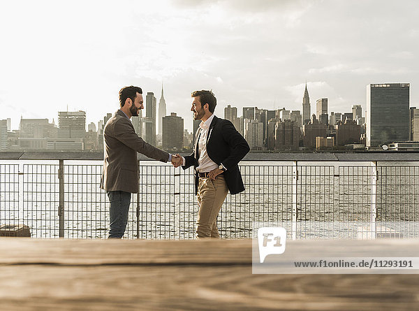 USA  New York City  zwei Geschäftsleute beim Händeschütteln am East River