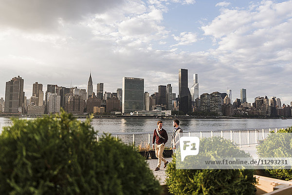 USA,  New York City,  zwei junge Männer entlang des East River
