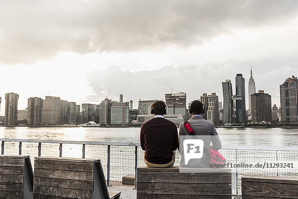 USA  New York City  Rückansicht von zwei Männern am East River mit Kopfhörern