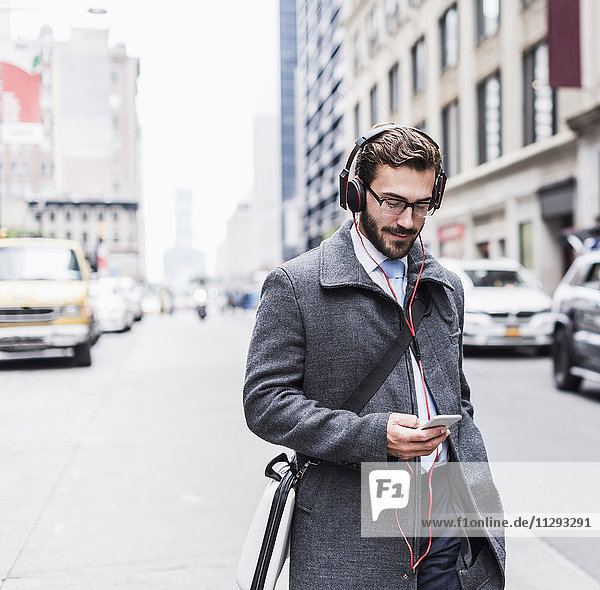 USA  New York City  businessman with cell phone and headphones on the go