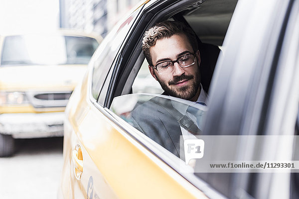USA  New York City  lächelnder Geschäftsmann im Taxi