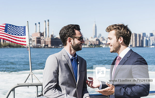 USA  New York City  two businessmen talking on ferry on East River