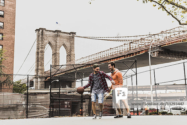 USA  New York  two young men playing basketball on an outdoor court