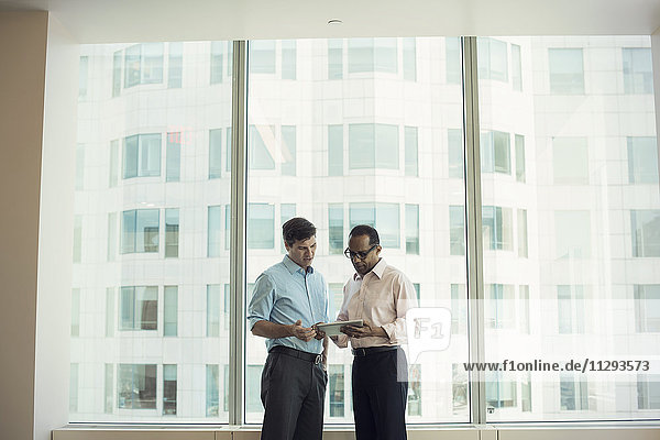 Business people with digital tablet standing by window