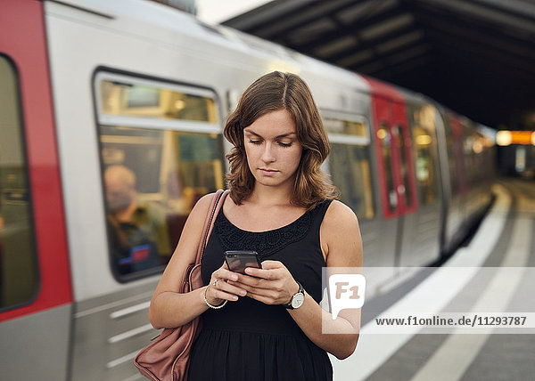 Deutschland  Junge Frau mit Smartphone erkundet Hamburg