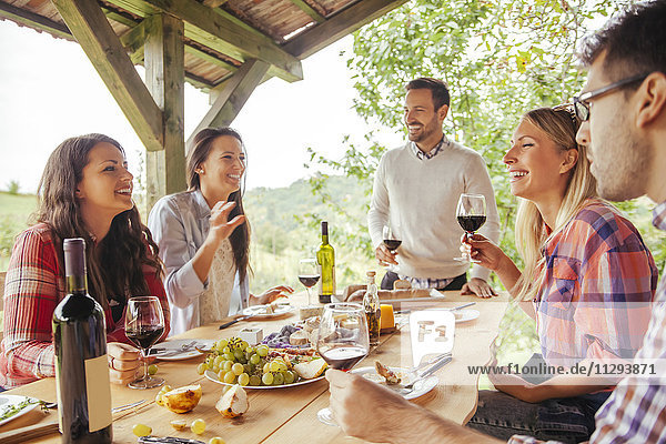Freunde treffen sich am Tisch im Freien bei Rotwein und kalten Snacks.