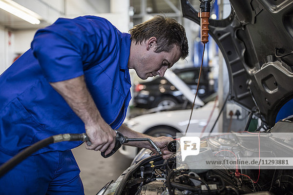 Kfz-Mechaniker in einer Werkstatt  die ein Auto repariert