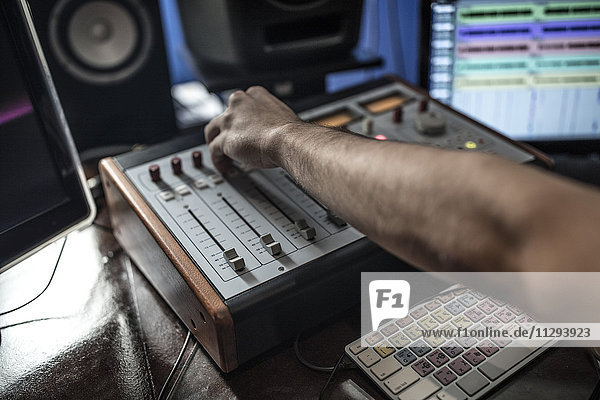 Close-up of audio engineer operating mixer in recording studio