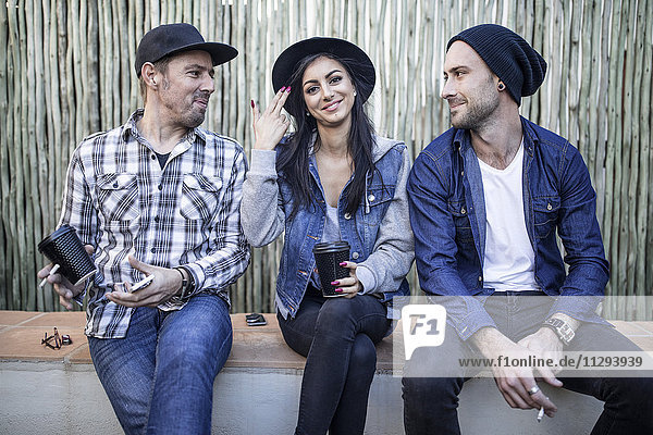 Portrait of young woman and two men sitting outdoors