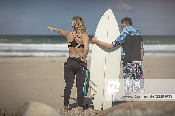 Teenage boy with down syndrome and woman with surfboard on beach