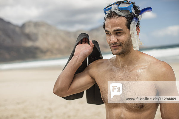 Young man with snorkeling equipment on the beach