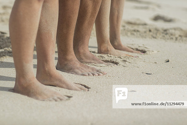 Feet of friends standing on the beach