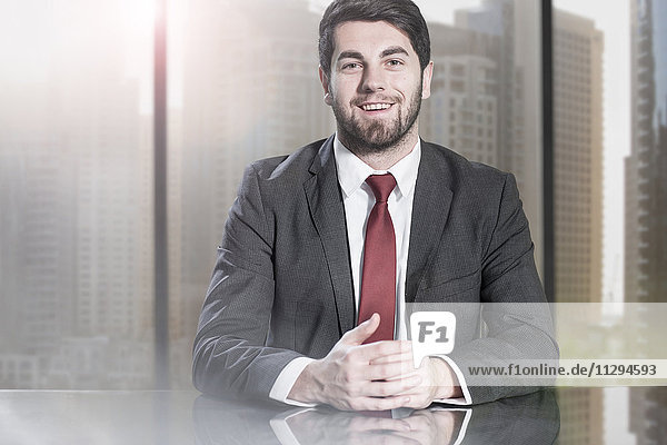 Young businessman sitting in office  looking at camera