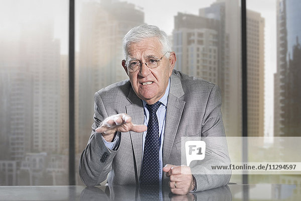 Senior businessman sitting in office  looking at camera