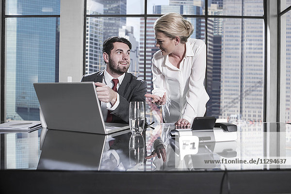 Businessman and woman in meeting discussing in office  using laptop