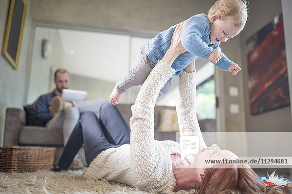 Mother lifting baby girl at home