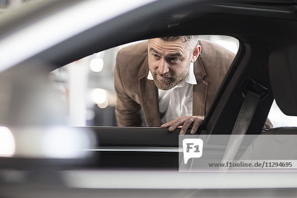 Man looking into car in car dealership