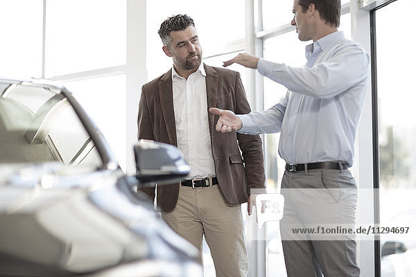 Car dealer talking to client in showroom