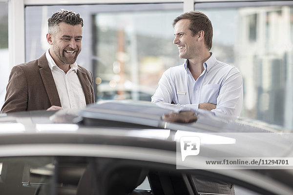 Car showing car to happy customer at car dealership