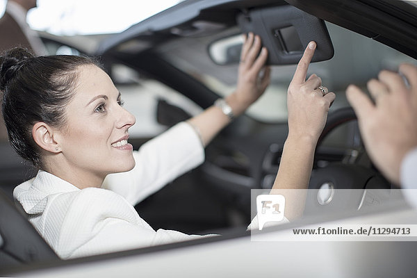 Lächelnde Frau sitzt im Auto beim Autohaus