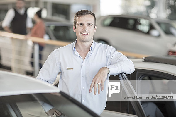 Portrait of confident car dealer in showroom