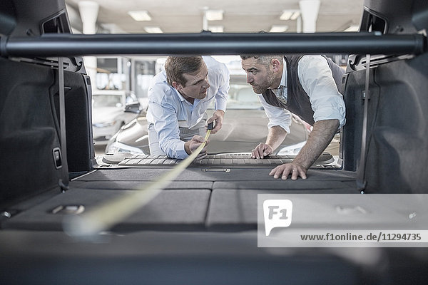 Car dealer measuring trunk of car at car dealership