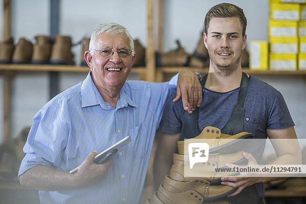 Portrait of smiling senior man and young man holding shoes