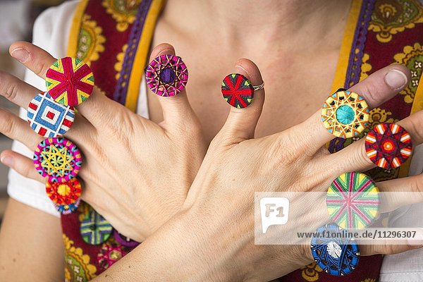 Knopfmacherin  junge Frau präsentiert an beiden Händen an Fingern aufgesteckt eine Auswahl von zehn Posamentenknopf Ringen  Ichenhausen  Bayern  Deutschland  Europa