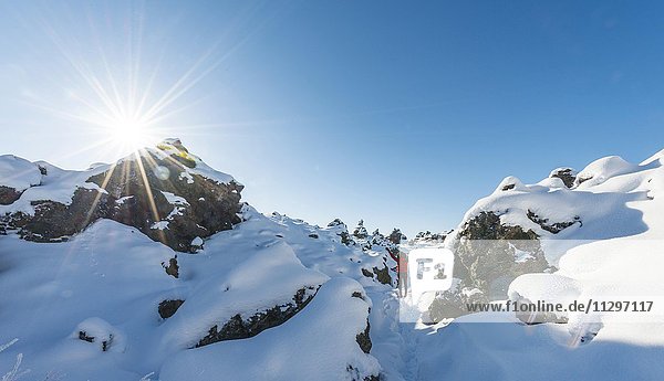Frau mit ausgestreckten Armen  Schneelandschaft bei Sonnenschein  Lavafeld bedeckt mit Schnee  Vulkansystems Krafla  Dimmuborgir Nationalpark  Mývatn  Nordisland  Island  Europa