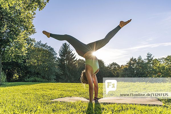 Handstand Junge Frau in Sportkleidung trainiert auf einer Matte in der Wiese in einem Park München Oberbayern Bayern Deutschland Europa