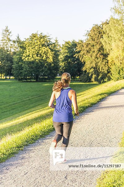 Junge Frau in Sportkleidung joggt in einem Park  München  Oberbayern  Bayern  Deutschland  Europa