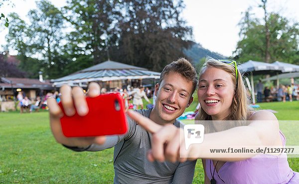 Junger Mann und junge Frau lächelt  schauen zusammen in ein Handy  Bayern  Deutschland  Europa