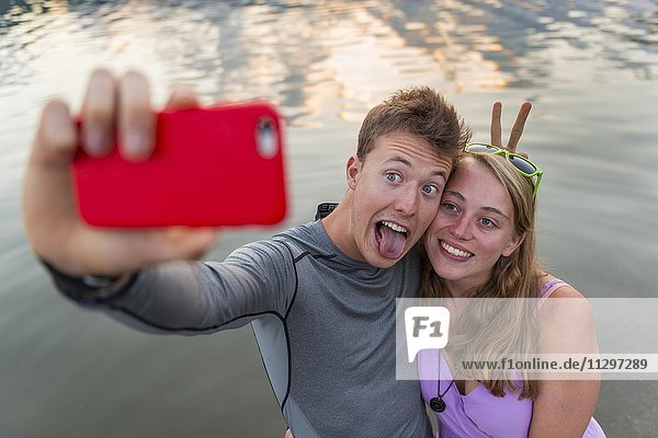 Junges Paar fotografiert sich mit einem Handy selbst Selfie Schliersee Oberbayern Bayern Deutschland Europa