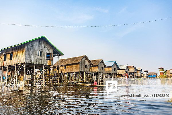 Holzboot mit Einheimischen vor traditionelle Stelzenhäusern am Inle-See  Inle Lake  Nampan  Shan Staat  Myanmar  Asien
