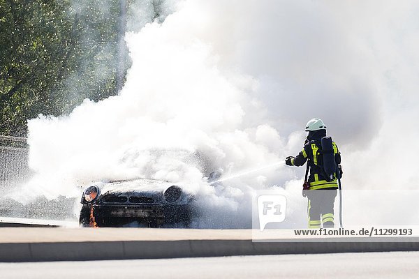 Feuerwehrmann löscht brennendes Auto  Deutschland  Europa