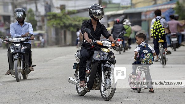 Mopeds and child with bike on the road  Phnom Penh  Cambodia  Asia