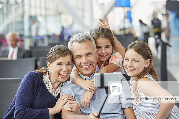 Familie nimmt Selfie mit Selfie-Stick am Flughafen mit